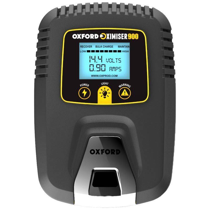 Oxford Oximiser 900 battery charger features a sleek black design with a digital display showing voltage and amperage, along with power, light, and warning indicators.