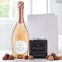 Rosé Prosecco bottle with copper foil, 12 chocolate truffles in black box, and a white occasion card.