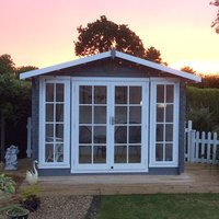 Gray wooden log cabin summerhouse with white-framed glass double doors and windows, set on a wooden deck.