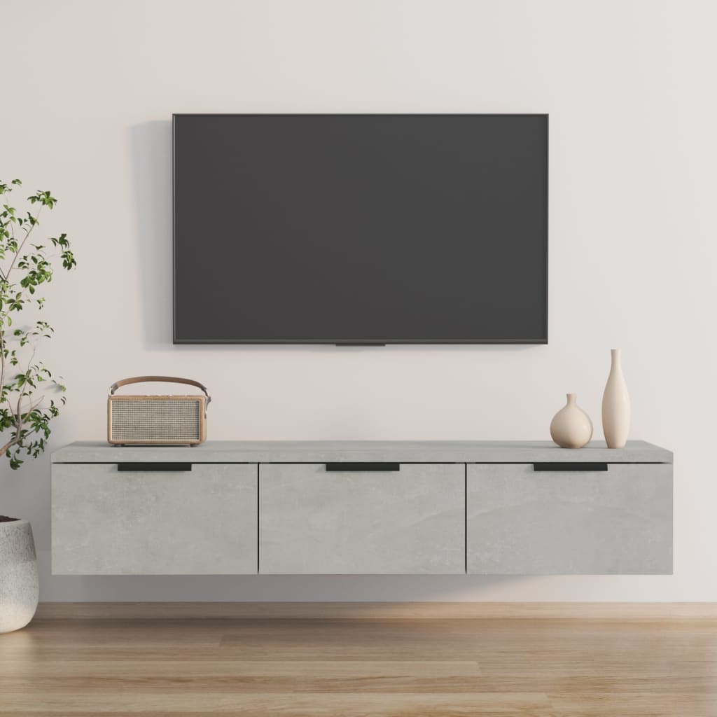 Concrete grey wall cabinet made of engineered wood, featuring three drawers with sleek black handles, positioned beneath a flat-screen TV, complemented by decorative vases and a plant.