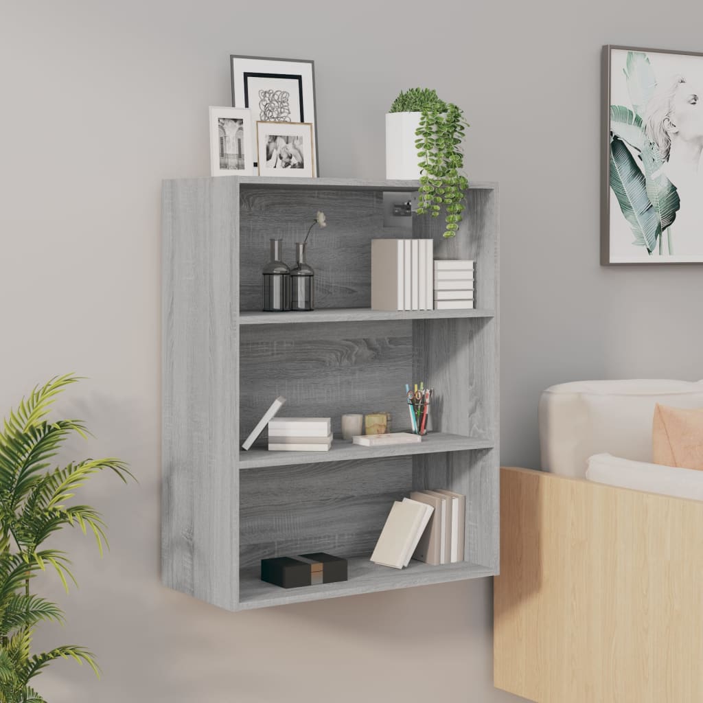 Grey Sonoma wall cabinet with three shelves, featuring decorative items, books, and a potted plant, mounted against a light wall, complemented by a nearby sofa.