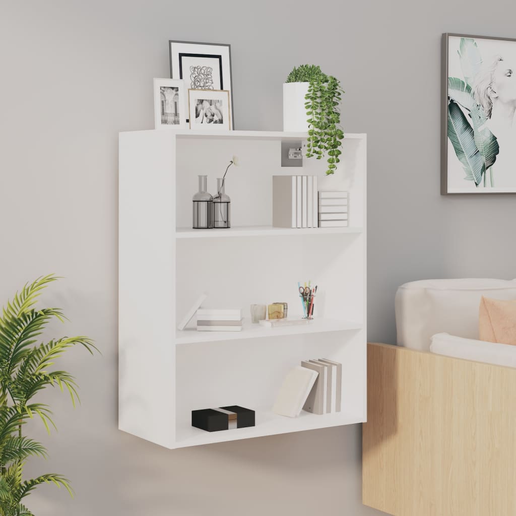 White hanging wall cabinet with three open shelves, featuring decorative items like vases and frames, set against a light gray wall with a plant and a sofa nearby.