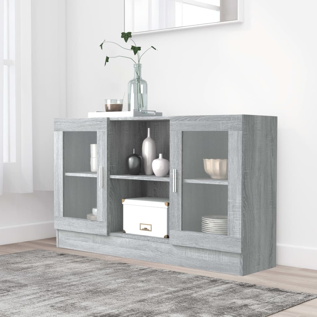 Grey Sonoma vitrine cabinet made of engineered wood, featuring two glass doors, open shelving, and a minimalist design, complemented by decorative items on top.