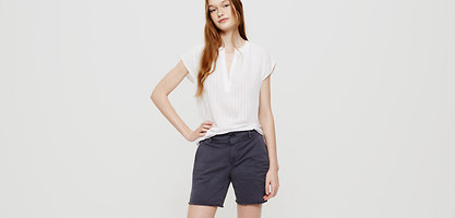 Chino shorts in dark navy with a relaxed fit, featuring a classic five-pocket design, paired with a light white blouse for a casual look.