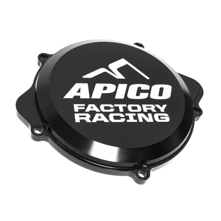 Black aluminum clutch cover with a glossy finish, featuring a prominent white "APICO FACTORY RACING" logo and four mounting holes, designed for KTM SX85 and Husqvarna TC85 models.