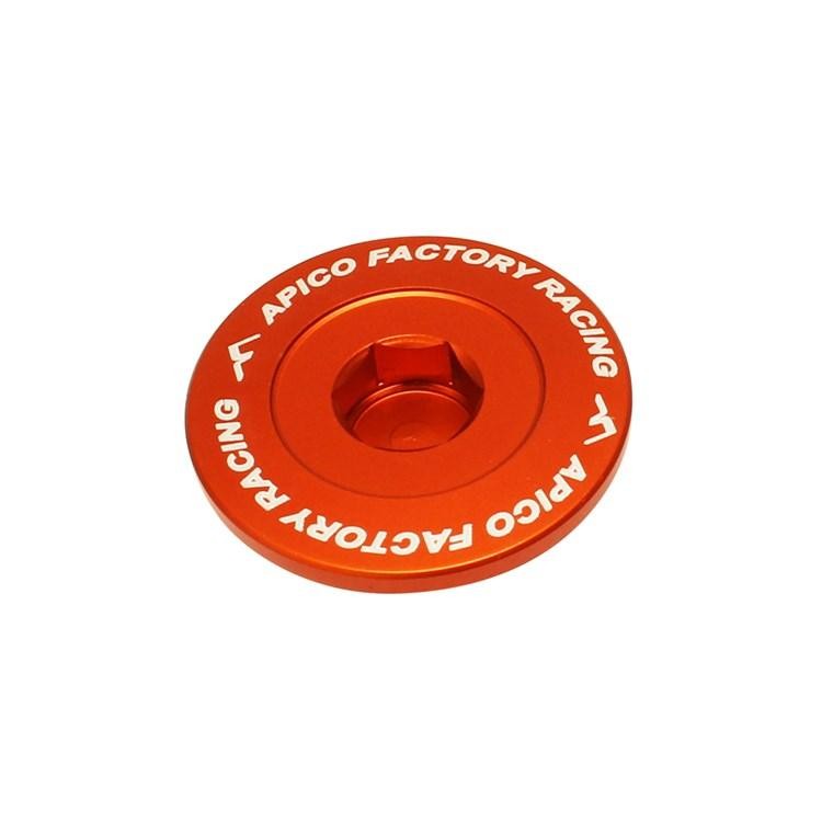 Orange anodized aluminum engine plug with a central hexagonal socket, featuring white "APICO FACTORY RACING" text around the edge, designed for KTM SXF models 2011-2024.