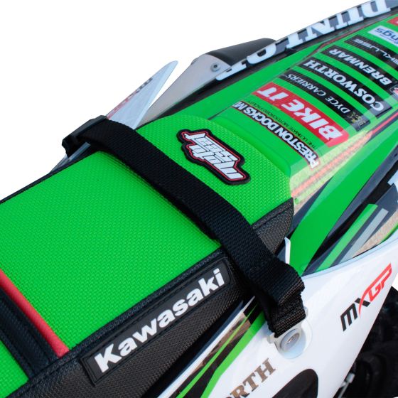 Bright green textured rear grab strap with black adjustable straps, featuring a logo and mounted on a motorcycle seat with visible branding and graphics.
