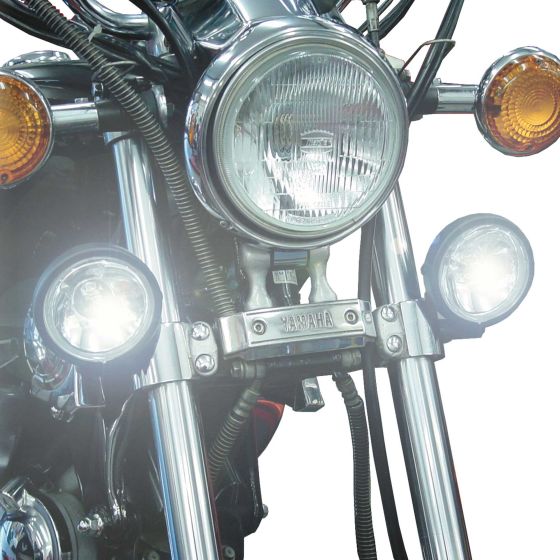 Universal twin spot lights with halogen H3-12V bulbs, featuring a chrome finish, mounted on a motorcycle, with bright white light illuminating the front.