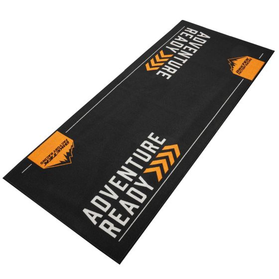 Black carpet with "ADVENTURE READY" in bold orange letters, featuring a mountain graphic and white lines along the edges, designed for outdoor and biking enthusiasts.