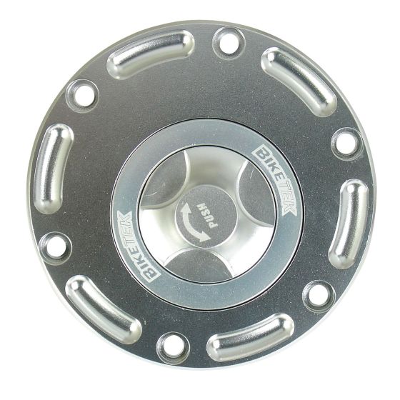 Silver aluminum quarter turn keyless race fuel filler cap with a circular design, featuring six cutouts and engraved "BIKETEK" logo, designed for Aprilia motorcycles.