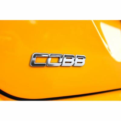 Chrome "COBB" badge made of ABS plastic, featuring a sleek, modern font, mounted on a vibrant yellow surface, ideal for enhancing vehicle aesthetics.