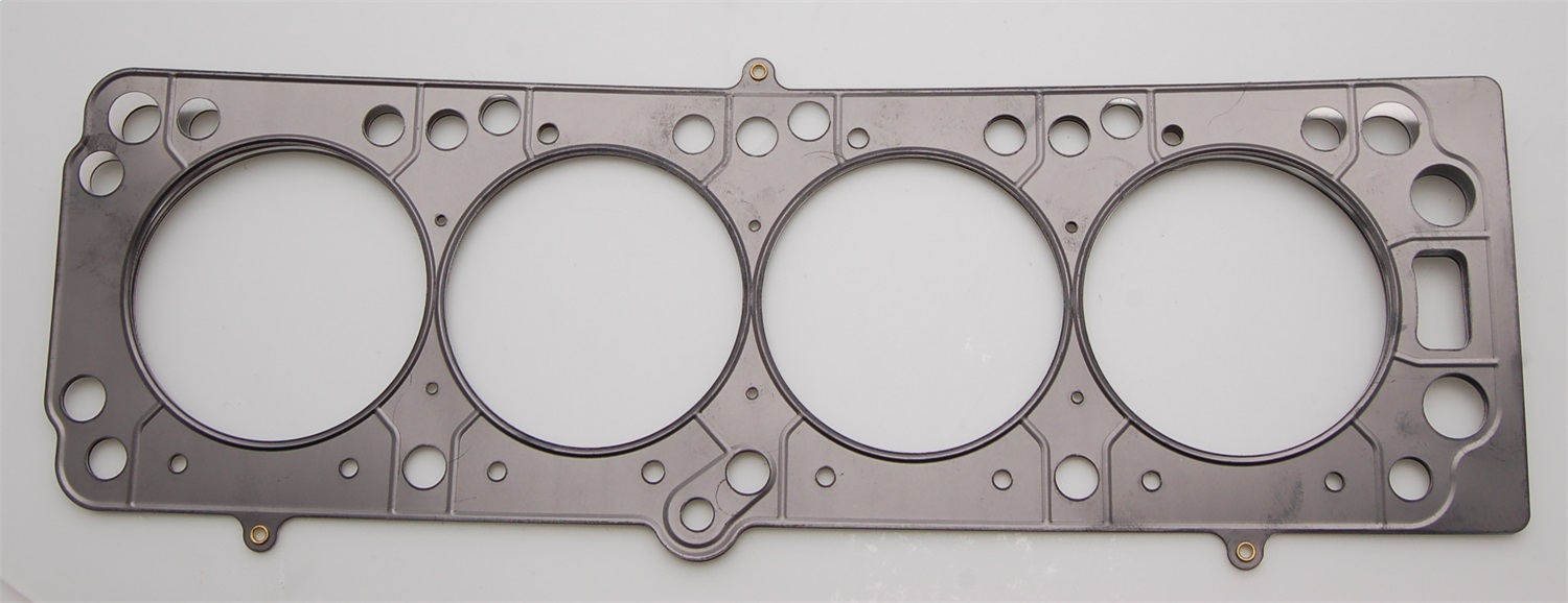Black metal head gasket with four circular cutouts, multiple bolt holes, and a smooth surface, designed for sealing engine components.
