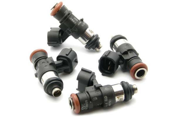 Four black and silver fuel injectors with orange seals and connectors, featuring a compact design and marked with DeatschWerks branding.