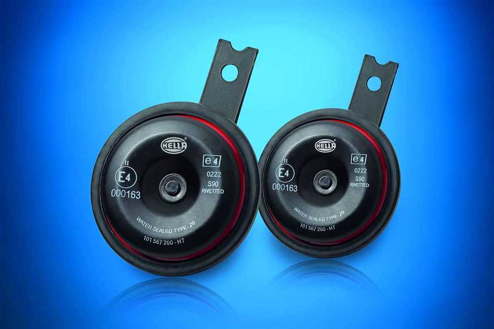 Two black automotive horns with a shiny finish, featuring a red accent ring, labeled "HELLA" and "E4," mounted on metal brackets against a blue background.