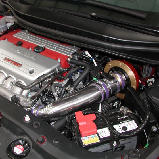 HKS Racing Suction Induction Kit featuring a polished aluminum intake pipe, purple silicone couplings, and a gold-colored air filter, installed in a red and silver engine bay.