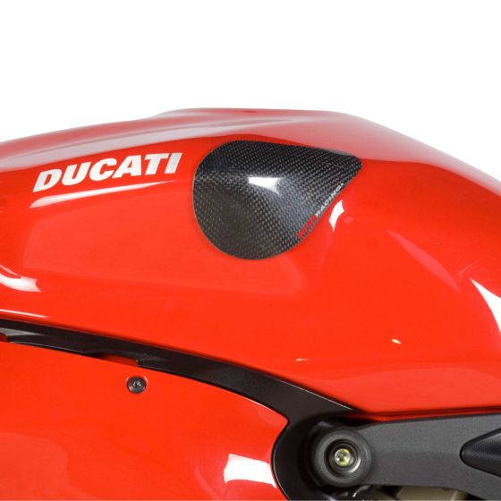 Carbon fibre tank sliders in a sleek black finish, designed for Ducati motorcycles, featuring a textured surface for grip against a vibrant red tank.
