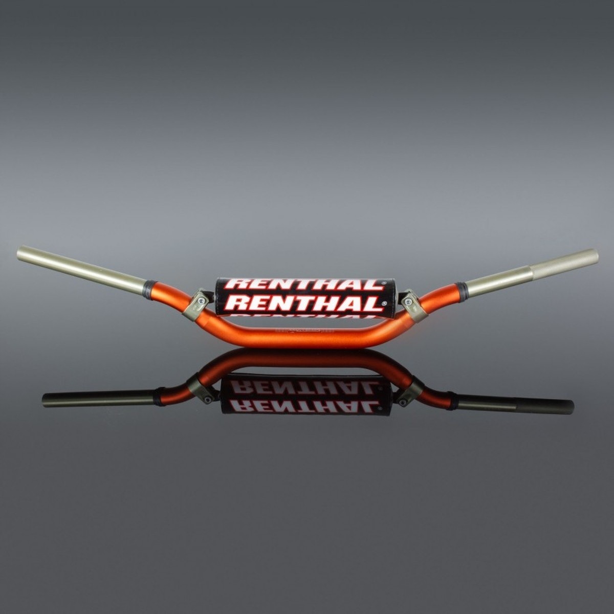 Orange Renthal 996 Twinwall handlebars with a distinctive bend, featuring a black and white Renthal logo on the center, and silver aluminum ends, reflecting on a smooth surface.