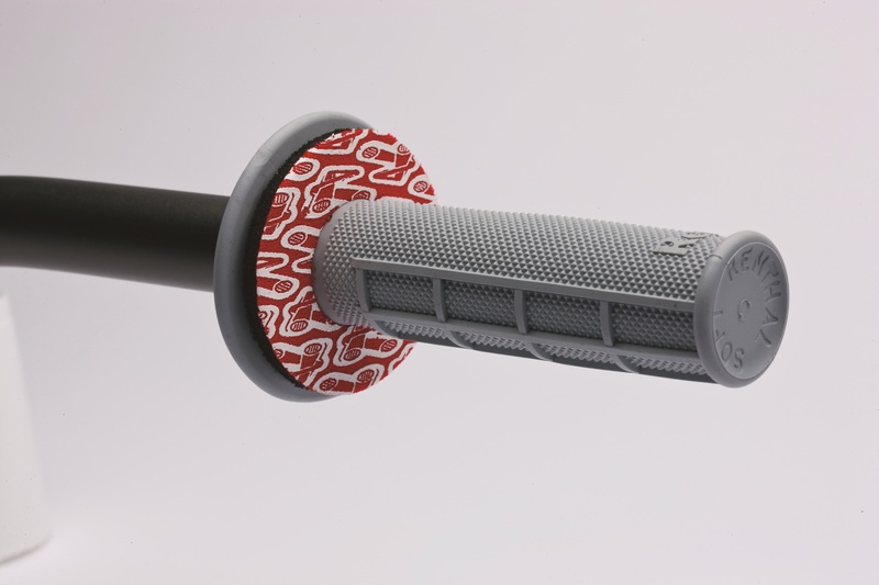 Gray rubber grip with textured surface, featuring a red and white Renthal logo donut at one end, attached to a black handlebar.