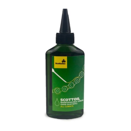 Green plastic bottle of Scottoiler chain oil with a black nozzle, featuring a label that reads "Scottoil" and highlights its biodegradable properties for all climates.