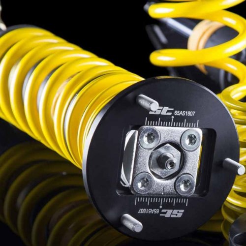 Yellow coil spring with a black adjustable top mount featuring silver hardware, designed for lowering vehicle height, part of the ST XTA Coilover Kit by ST Suspension.