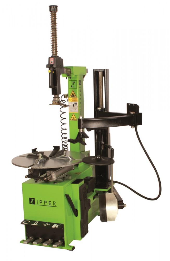 Green and black Zipper tire mounting machine with a vertical arm, adjustable clamp, and a rotating disc for tire installation, featuring safety labels and a sturdy build.