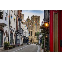 Charming Yorkshire street with historic buildings, colorful bunting, and a view of a large stone church in the background.