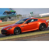Red Aston Martin V8 Vantage supercar on a racetrack with black alloy wheels and sleek aerodynamic design.