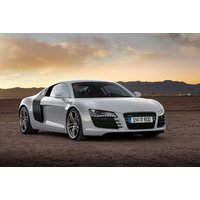 White Audi R8 supercar parked on desert terrain with mountains in the background.