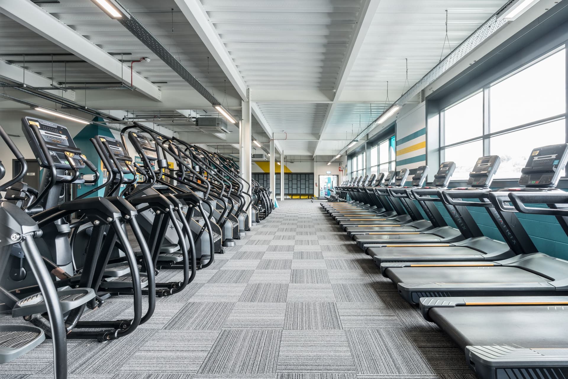 Modern gym with rows of treadmills and elliptical machines