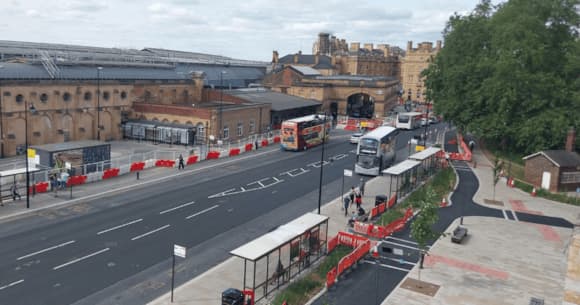 Historic York railway station with buses and red barriers