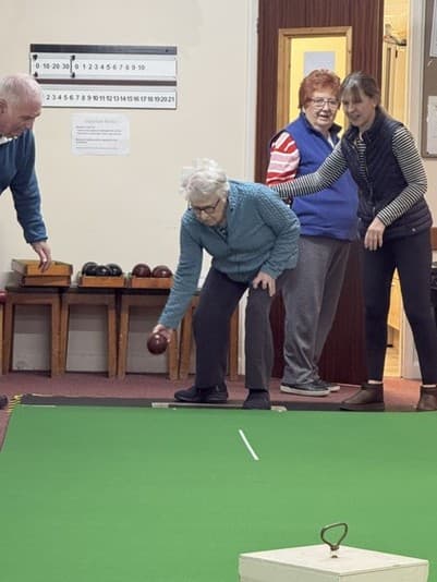 Group of elderly people playing indoor lawn bowls
