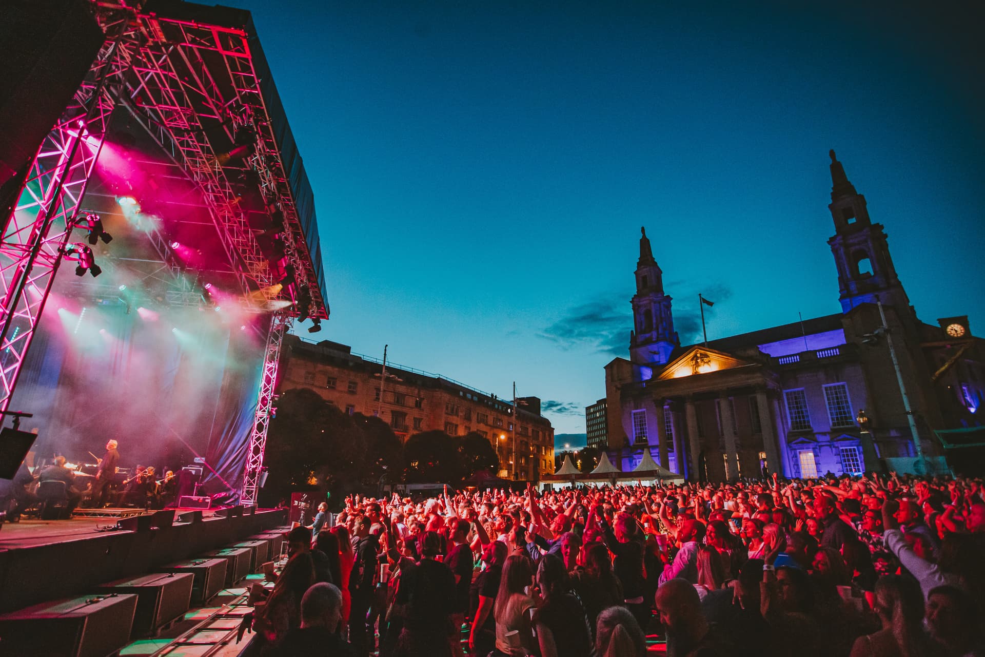 Outdoor concert with colorful lights and historic buildings
