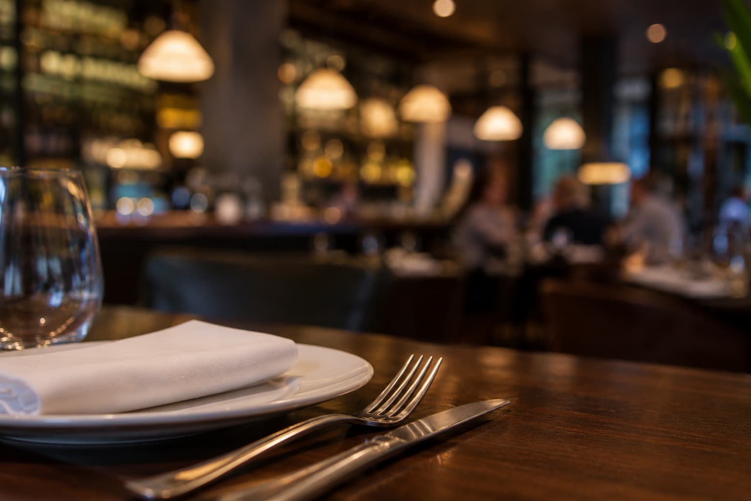 Elegant restaurant table setting with blurred diners