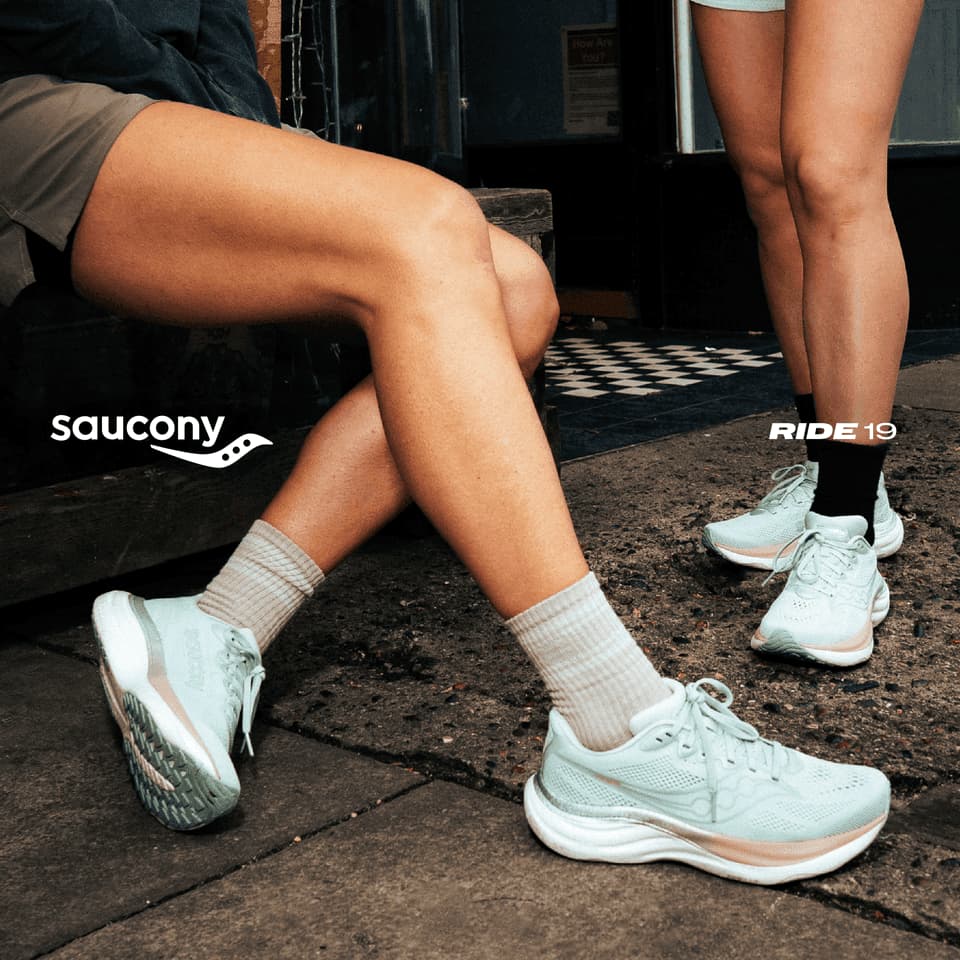 Two people wearing light blue running shoes on city pavement