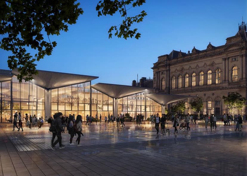 Modern glass pavilion and historic building at dusk