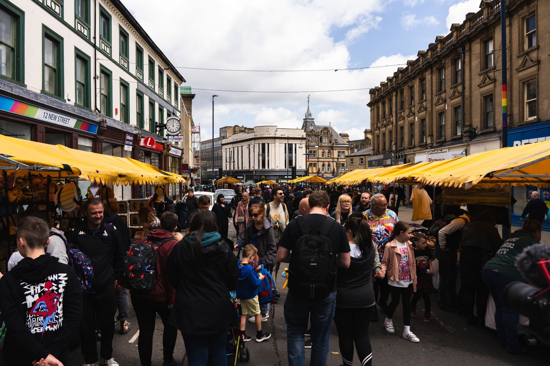 Crowded outdoor market with yellow stalls and historic buildings
