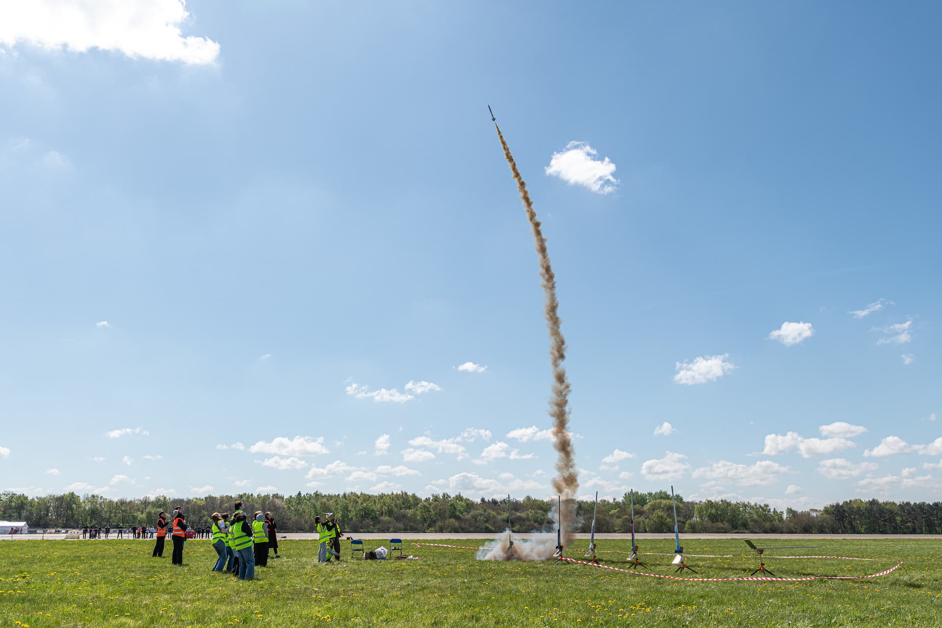 Rocket launching into blue sky from grassy field