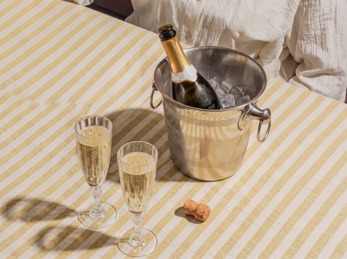 Chilled champagne bottle in ice bucket with two filled glasses