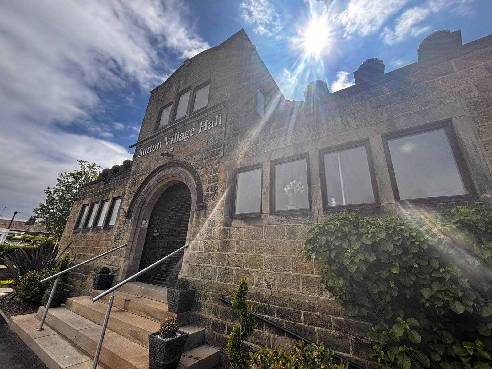 Stone village hall with arched entrance under bright sun