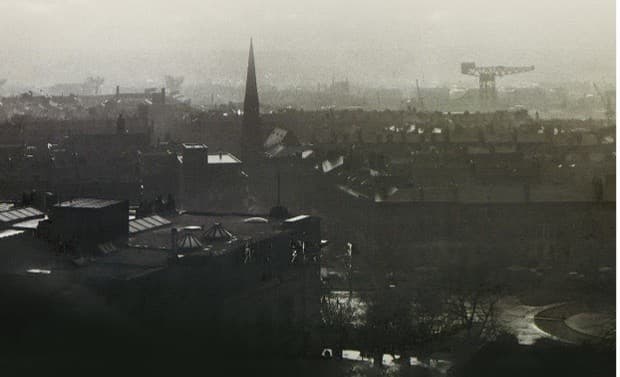 Misty skyline of industrial town with church spire and crane