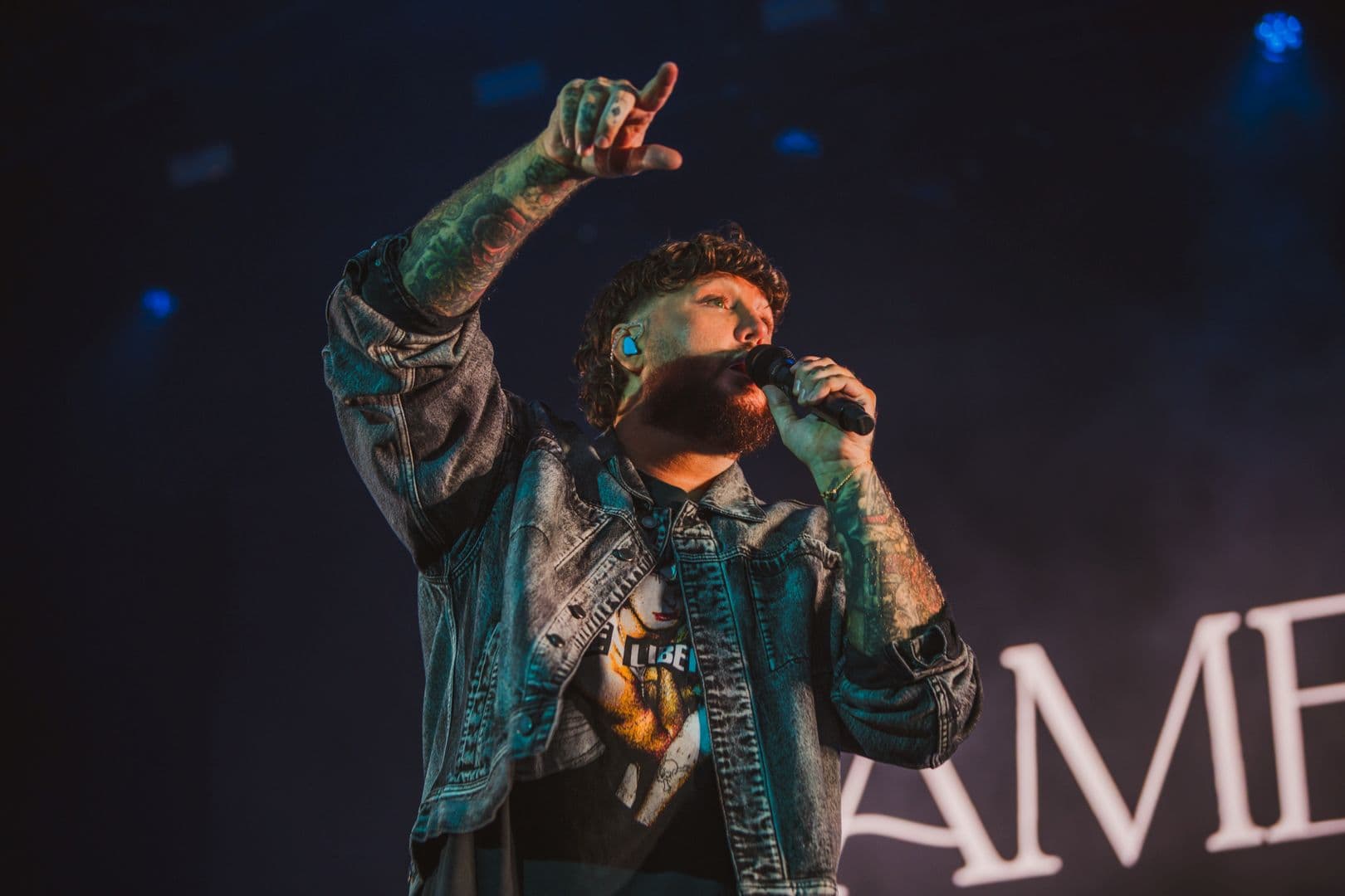 Singer performing on stage with microphone and denim jacket
