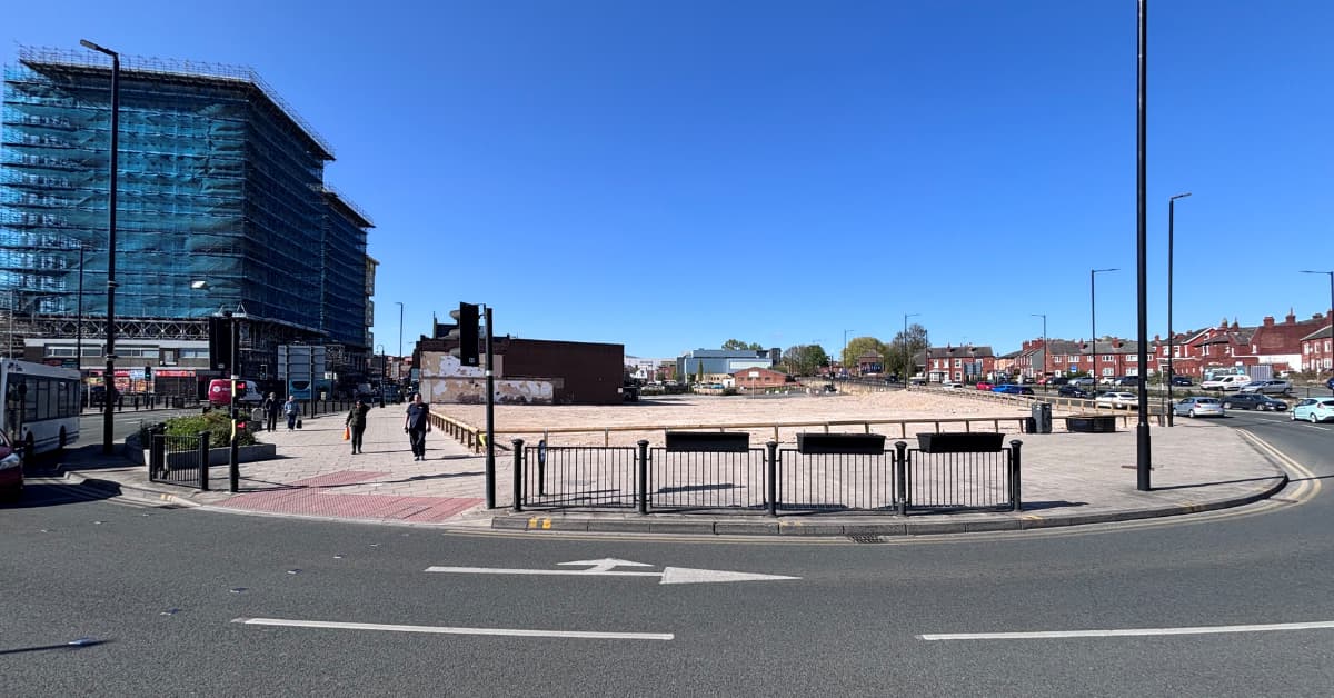 Urban street scene with construction site and red brick buildings