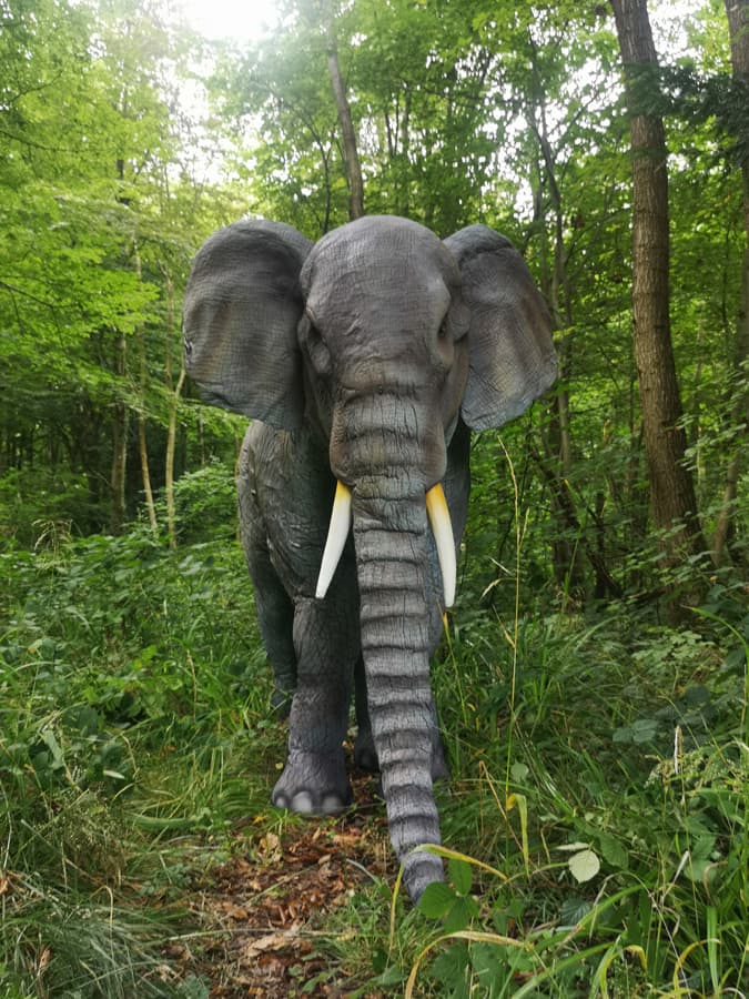 Lifelike elephant statue in lush green forest setting