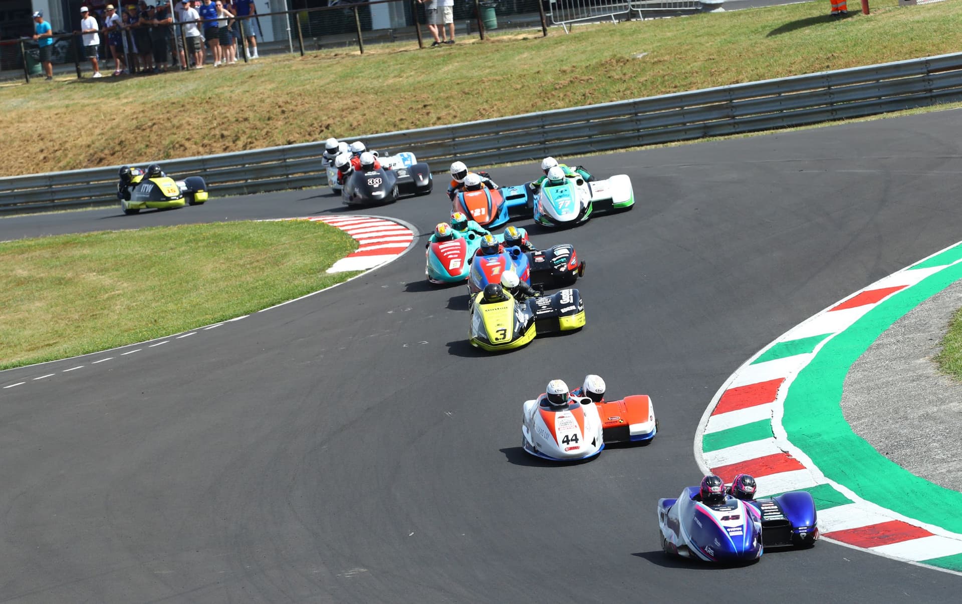 Motorcycle sidecars racing on a winding track with spectators