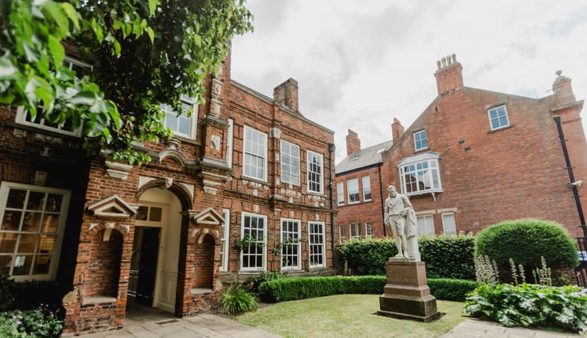 Historic brick building with statue in lush courtyard