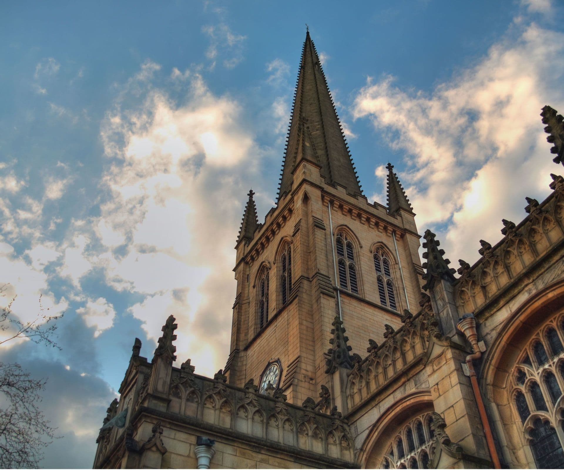 Gothic church spire reaching towards a cloudy blue sky