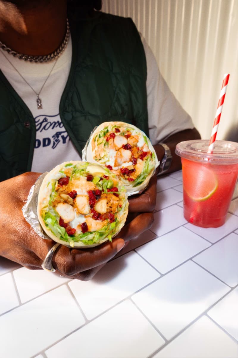 Person holding a chicken wrap with lettuce and cranberry