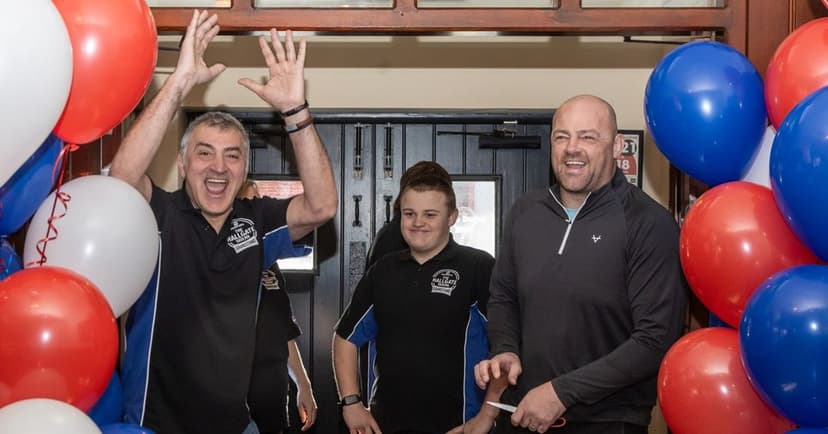 Cheerful pub staff celebrate at a Hull venue, surrounded by red, white, and blue balloons, as FA Cup excitement builds.