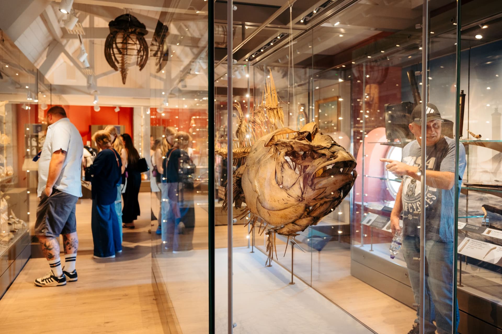 Museum visitors viewing maritime artefacts in glass cases