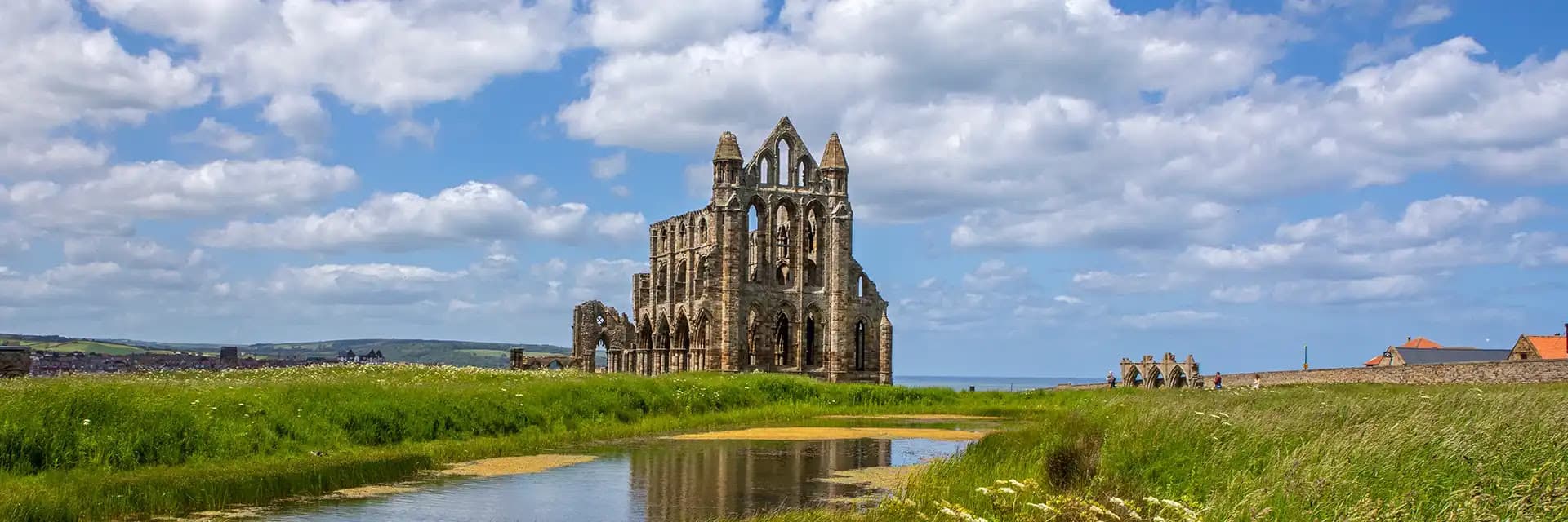 Whitby Abbey ruins on a hill under a cloudy blue sky